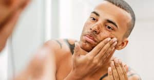 Licht getinte man met kort haar en tatoeage scrubt zijn gezicht