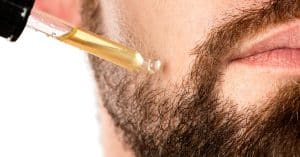 Man met baard gebruikt baardgroei serum met een pipet