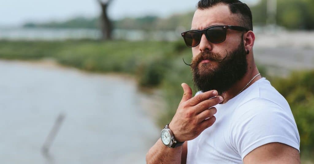 Man met baard, zwarte zonnebril en krul snorretje