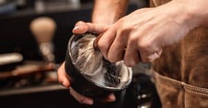 Handen met authentieke scheerkom en kwast