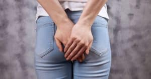 Vrouwelijk achterwerk in jeans met handen voor de billen.