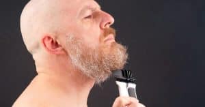 Man met kaal hoofd scheert zijn baard met een tondeuse