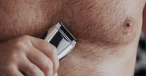 Mannen borstkas waarbij het haar wordt getrimd met een trimmer