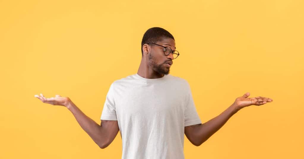 Man met wit t-shirt die beide handen omhoog houd alsof hij iets vergelijkt.