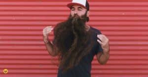 Man met hele lange bruine baard. Hij trekt met zijn handen aan zijn lange baard.